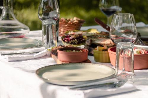a table with plates of food and wine glasses at Mimani Stone House Roshnik in Roshnik