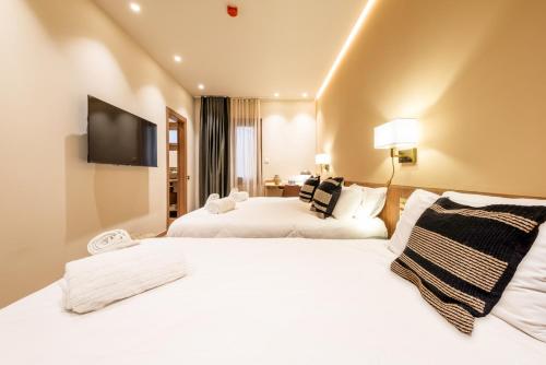 a hotel room with two beds and a flat screen tv at Hostal Ambos Mundos in Barcelona
