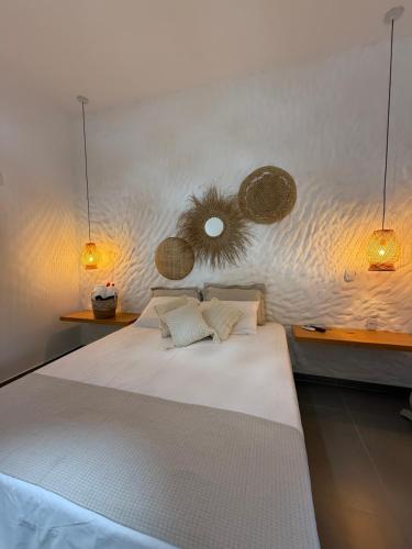 a bedroom with a large white bed with two lights at O Caminho das Dunas in Jericoacoara