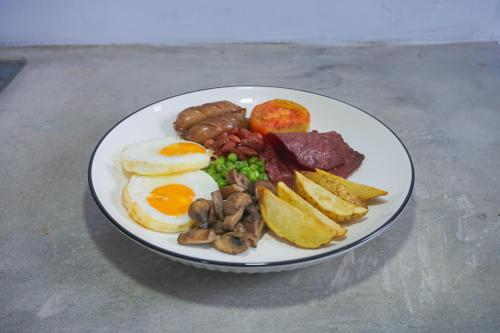 a plate of breakfast food with eggs meat and mushrooms at Treehita Cabin Jogja in Sleman