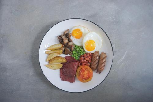 a plate of breakfast food with eggs meat and vegetables at Treehita Cabin Jogja in Sleman