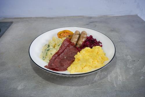 a plate of food with meat scrambled eggs and sausage at Treehita Cabin Jogja in Sleman