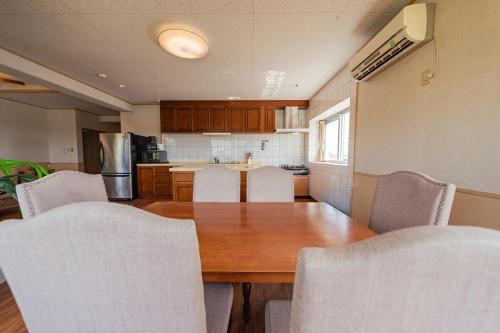 a kitchen with a wooden table and white chairs at unito villa OKINAWA Koza in Okinawa City