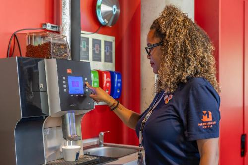 a woman standing in front of a coffee machine at MEININGER Hotel Paris Porte de Vincennes in Paris