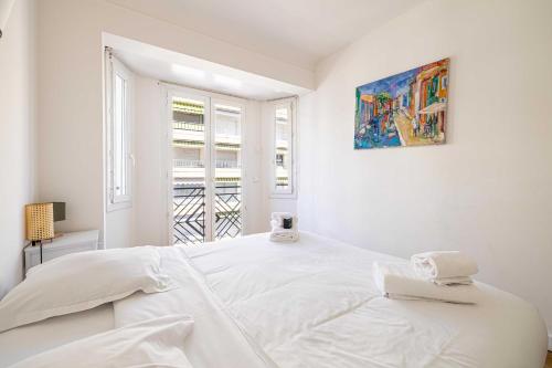 une chambre blanche avec un grand lit blanc et une fenêtre dans l'établissement Elegance and Refinement, proximity to La Croisette, à Cannes