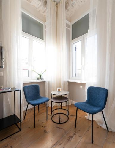 two chairs and a table in a room with windows at Agora apartment in Ermoupoli