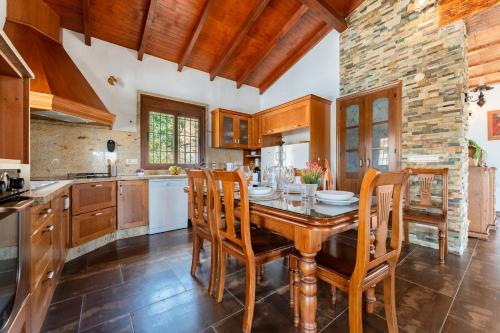 a kitchen with a wooden table and chairs at MalagaSuite Villa Rural Madeira in Algarrobo