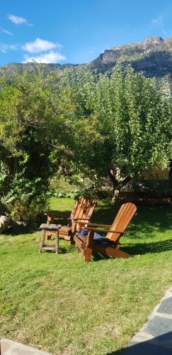 a group of chairs and a picnic table in the grass at La Estacion Hostel in Lago Puelo