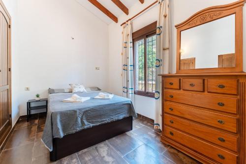 a bedroom with a bed and a dresser and a window at MalagaSuite Villa Rural Madeira in Algarrobo