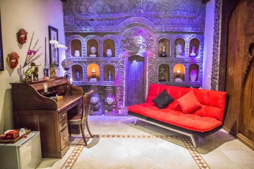 a living room with a red couch and a piano at Avalon Ubud Castle & SPA in Ubud