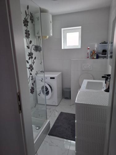 a bathroom with a sink and a washing machine at Sunshine apartments in Karlobag