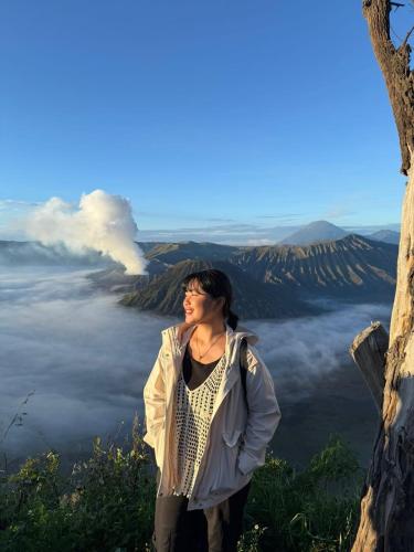 a woman standing on top of a mountain with a eruption at Ikiikahomestay in Probolinggo