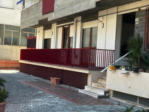 a building with a red fence and a porch at Casa Neghelli - Alassio in Alassio