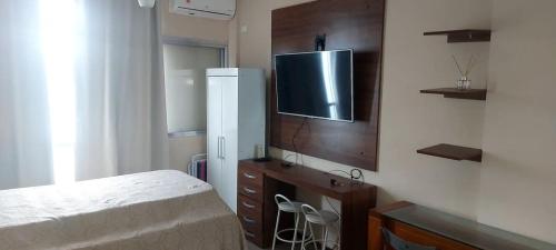 a bedroom with a bed and a tv on a wall at Kitão PÉ na Areia in São Vicente