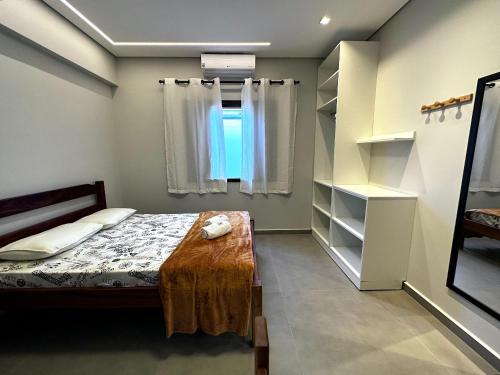 a bedroom with a bed and a window and shelves at Apto Funcional próximo a Orla do Centro HS2 in Ubatuba