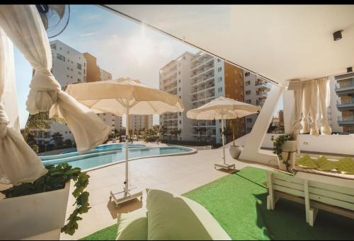 a patio with umbrellas and a swimming pool at Bedroom flat Caesar resort, Iskele north Cyprus in Vrysoules