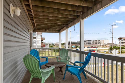 a porch with three chairs and a table at Salty Vibes in Nags Head
