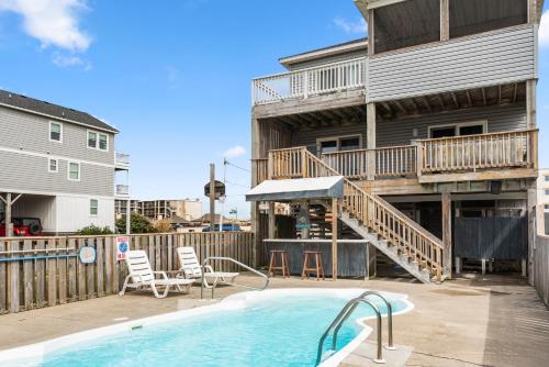 a swimming pool with a deck and a house at Salty Vibes in Nags Head