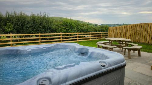 a hot tub in a backyard with a picnic table at Daverneithon 2 in Rhayader