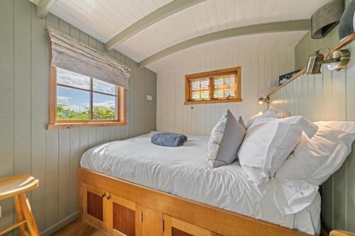 a bedroom with a bed with white sheets and a window at Corry Lodge Estate - Sheperds Huts or Container Stays with Sea View in Broadford