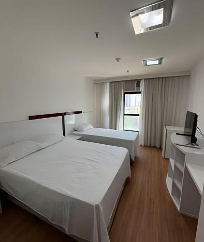 a hotel room with two beds and a television at Flat em Hotel, Até 4 Hóspedes, Piscina, Garagem , Jr Catito in Brasilia