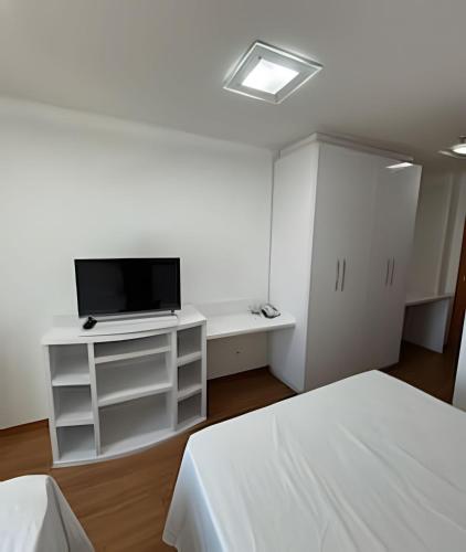 a white room with a tv and a bed at Flat em Hotel, Até 4 Hóspedes, Piscina, Garagem , Jr Catito in Brasilia
