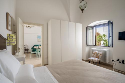 a white bedroom with a bed and a dining room at Dimora EgiLò in Nardò