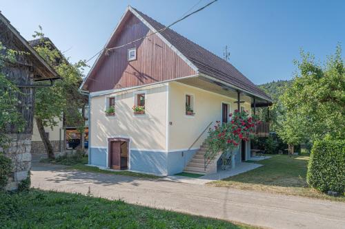 a white and blue house with flowers on the windows at Vineyard cottage Kolpa Zupančič in Stari Trg ob Kolpi