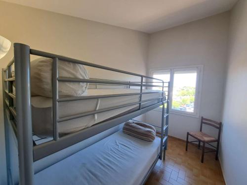 - une chambre avec 2 lits superposés et une chaise dans l'établissement Appartement 3 pièces climatisé à 400m de la plage et commerces - Grau d'Agde - FR-1-423-261, au Grau-dʼAgde