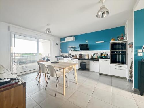 une cuisine avec des murs bleus et une table et des chaises dans l'établissement Charmant appartement PMR avec terrasse, climatisation et parking à Palavas - FR-1-559-42, à Palavas-les-Flots