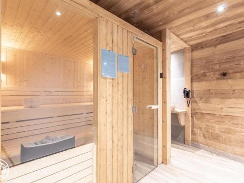 un sauna avec des murs en bois et une porte en verre dans l'établissement Appartement cosy avec sauna et spa, pied des pistes - FR-1-467-141, au Grand-Bornand