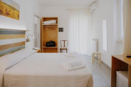 a white room with a bed and a chair at Le Vie di Feronia in Terracina