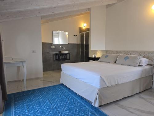 a bedroom with a large white bed and a bathroom at Tenuta Feraxi - Private Paradise in San Priamo