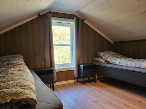 a attic bedroom with two beds and a window at Hytte ved sjøen in Røyra