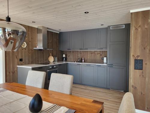 a kitchen with blue cabinets and a table and chairs at Hytte ved sjøen in Røyra