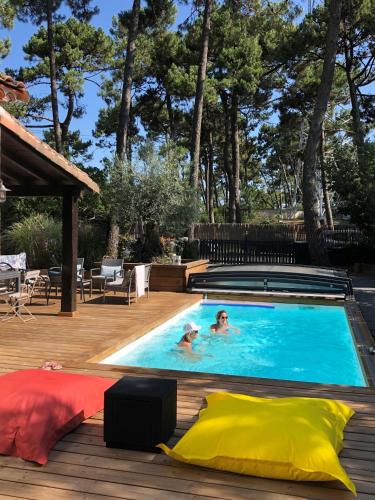 2 personnes se baignant dans une piscine sur une terrasse dans l'établissement Chambre Privative, Cap Ferret - Piscine Chauffée - Villa Sylhengui, à Lège-Cap-Ferret