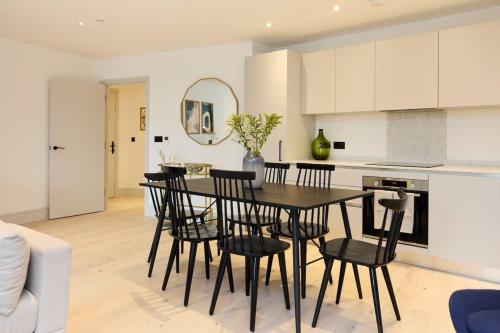 a kitchen and dining room with a black table and chairs at The South Wimbledon Place - Adorable 2BDR Flat with Balcony in London