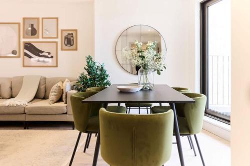 a living room with a table and green chairs at The South Wimbledon Escape - Lovely 3BDR with Balcony in London