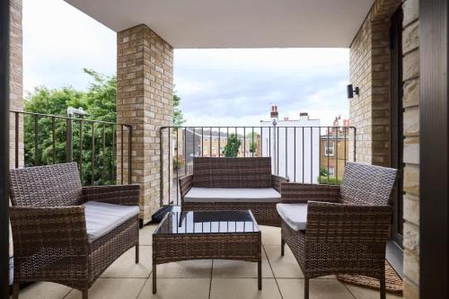 a balcony with wicker chairs and a coffee table at The South Wimbledon Escape - Lovely 3BDR with Balcony in London