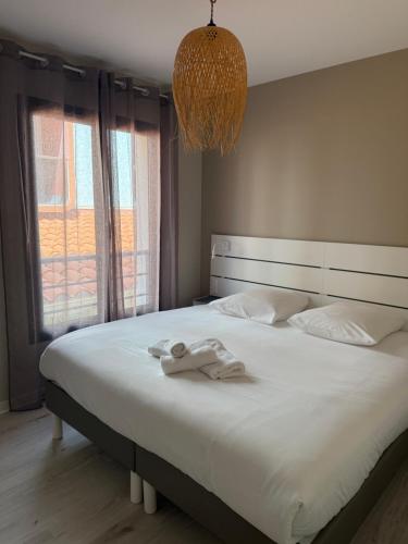 a bedroom with a large white bed with a chandelier at Hotel Aquarius in Canet-en-Roussillon