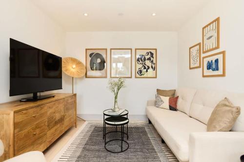 a living room with a white couch and a television at The South Wimbledon Hideout - Fancy 1BDR Flat with Balcony in London