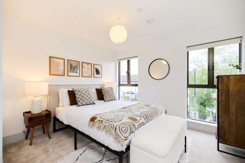 a white bedroom with a bed and a window at The South Wimbledon Hideout - Fancy 1BDR Flat with Balcony in London