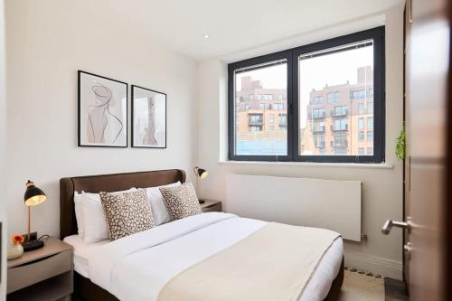 a bedroom with a large white bed and a window at The Harlesden Breakout - Glamorous 2BDR Flat in London