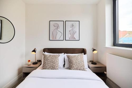 a white bedroom with a bed and two lamps at The Harlesden Breakout - Glamorous 2BDR Flat in London