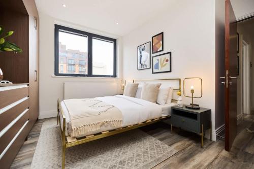 a white bedroom with a bed and a window at The Harlesden Breakout - Glamorous 2BDR Flat in London