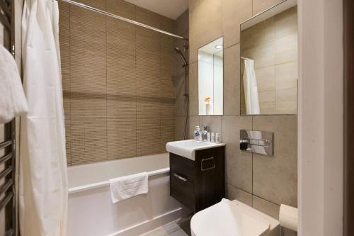 a bathroom with a sink and a toilet and a tub at The Harlesden Breakout - Glamorous 2BDR Flat in London
