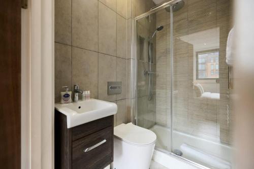 a bathroom with a toilet and a sink and a shower at The Harlesden Breakout - Glamorous 2BDR Flat in London