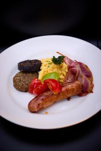 a white plate of food with sausage and eggs and meat at Tannery Townhouse in Dungarvan