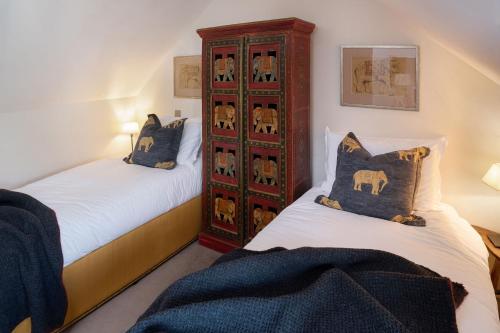 a bedroom with two beds and a wooden cabinet at The Garden House in Bath