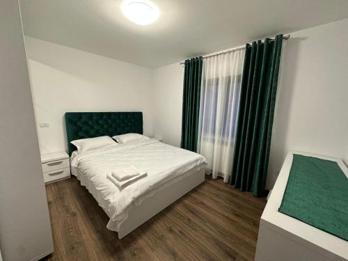 a bedroom with a white bed and green curtains at Casa Daria in Moisei